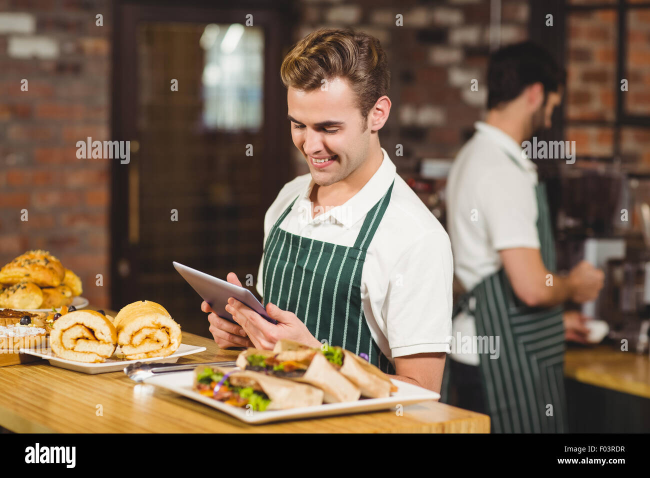 Smiling waiter using a digital tablet Banque D'Images