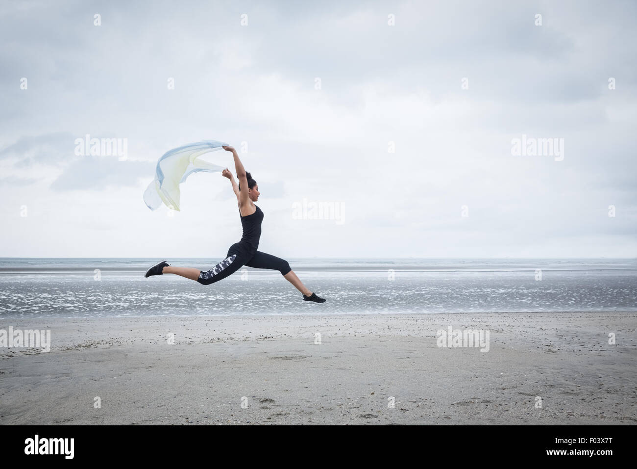 Fit girl leaping avec écharpe Banque D'Images