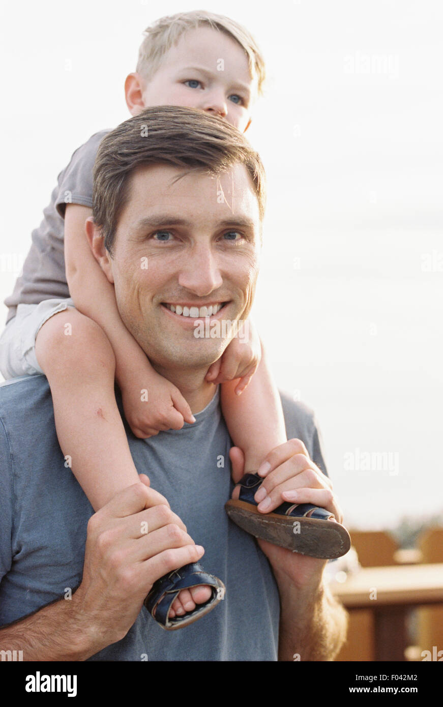 Smiling man carrying son jeune fils sur ses épaules. Banque D'Images