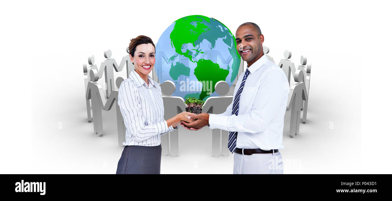 Image composite des collègues d'affaires holding plant and looking at camera Banque D'Images