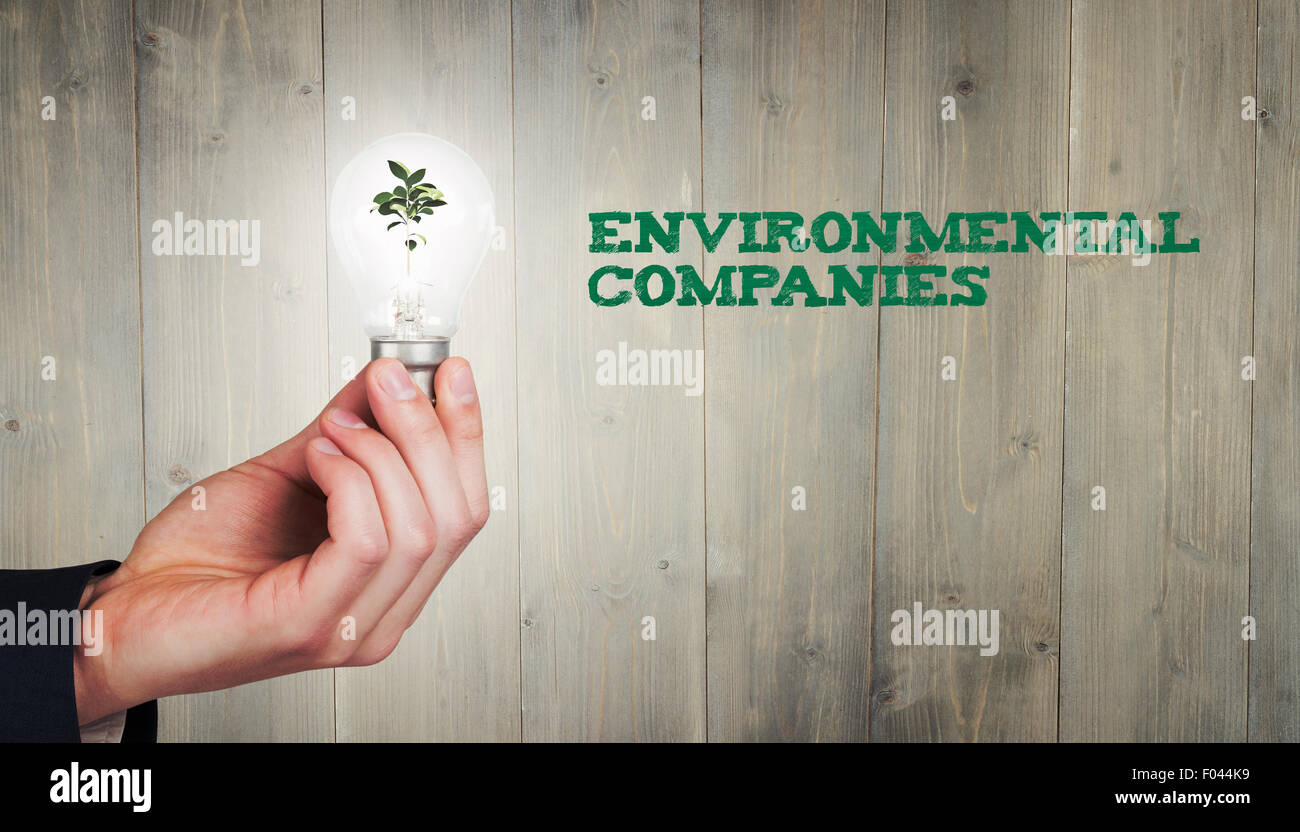 Image composite de la main qui tient l'ampoule de l'environnement Banque D'Images