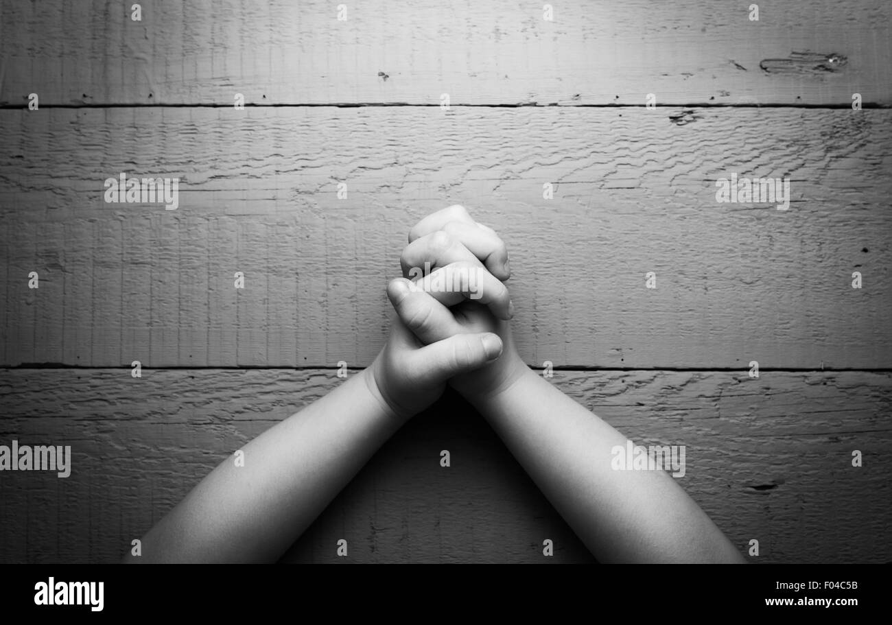 Les mains de l'enfant pliées ensemble dans la prière. Photo en noir et blanc Banque D'Images
