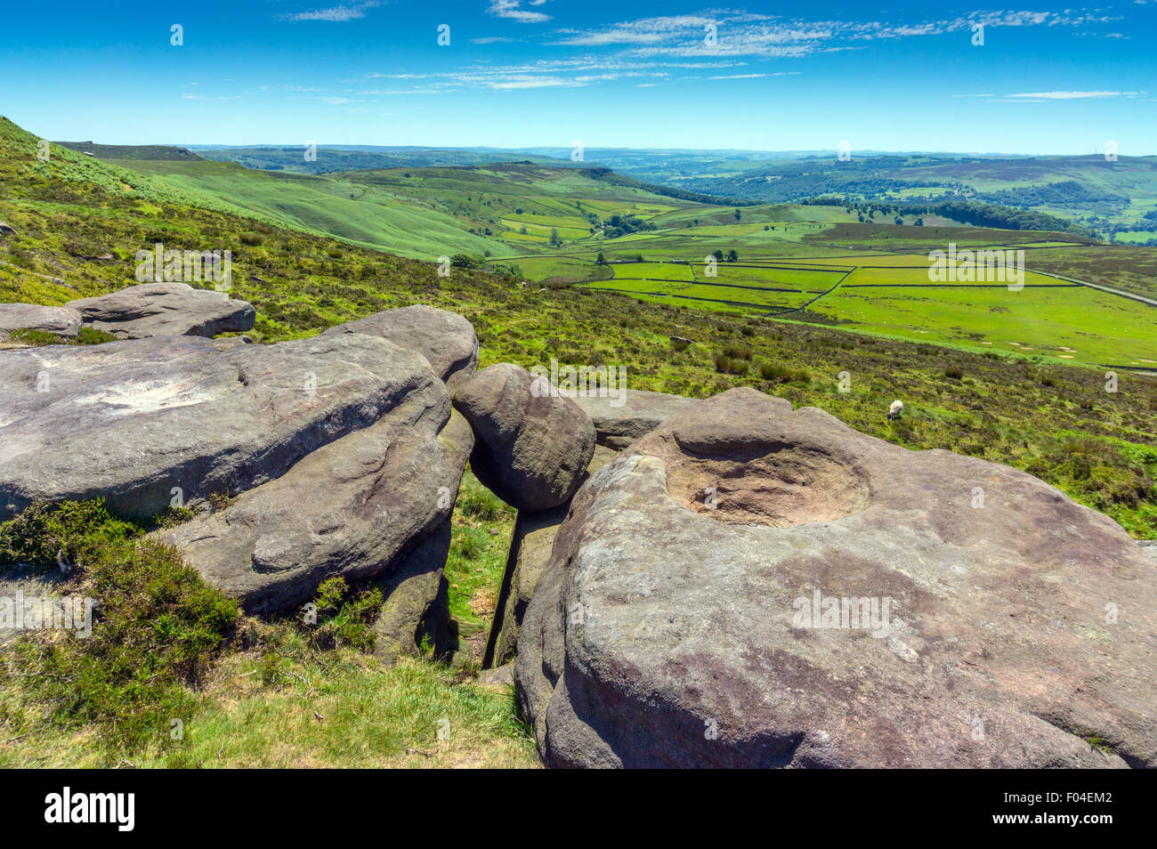 Vue ouest à partir de la pierre meulière falaise de Stanage Edge, parc national de Peak District, Derbyshire, avec des rochers en premier plan Banque D'Images