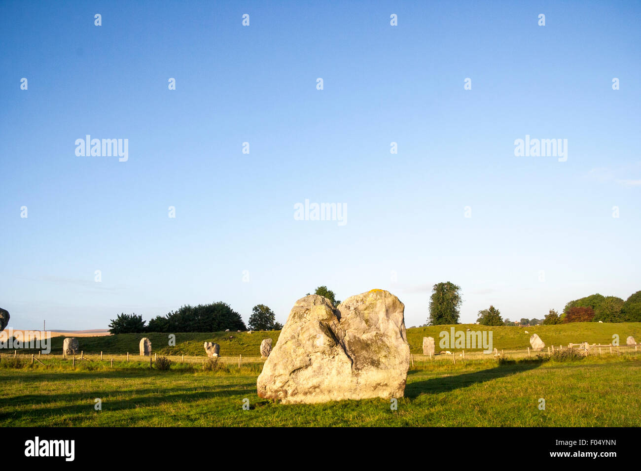 D'Avebury néolithique. Pierre du sud du cercle intérieur ; arrière-plan, une ligne de mégalithes et pierres remblai earthern et ciel bleu. Banque D'Images