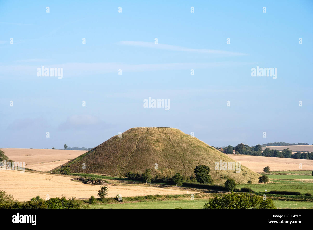 De lointaines Silbury Hill, les tumulus néolithique en Angleterre. A 40 mètres de haut monticule d'herbe à l'homme debout la tête dans le paysage relativement plat. Banque D'Images