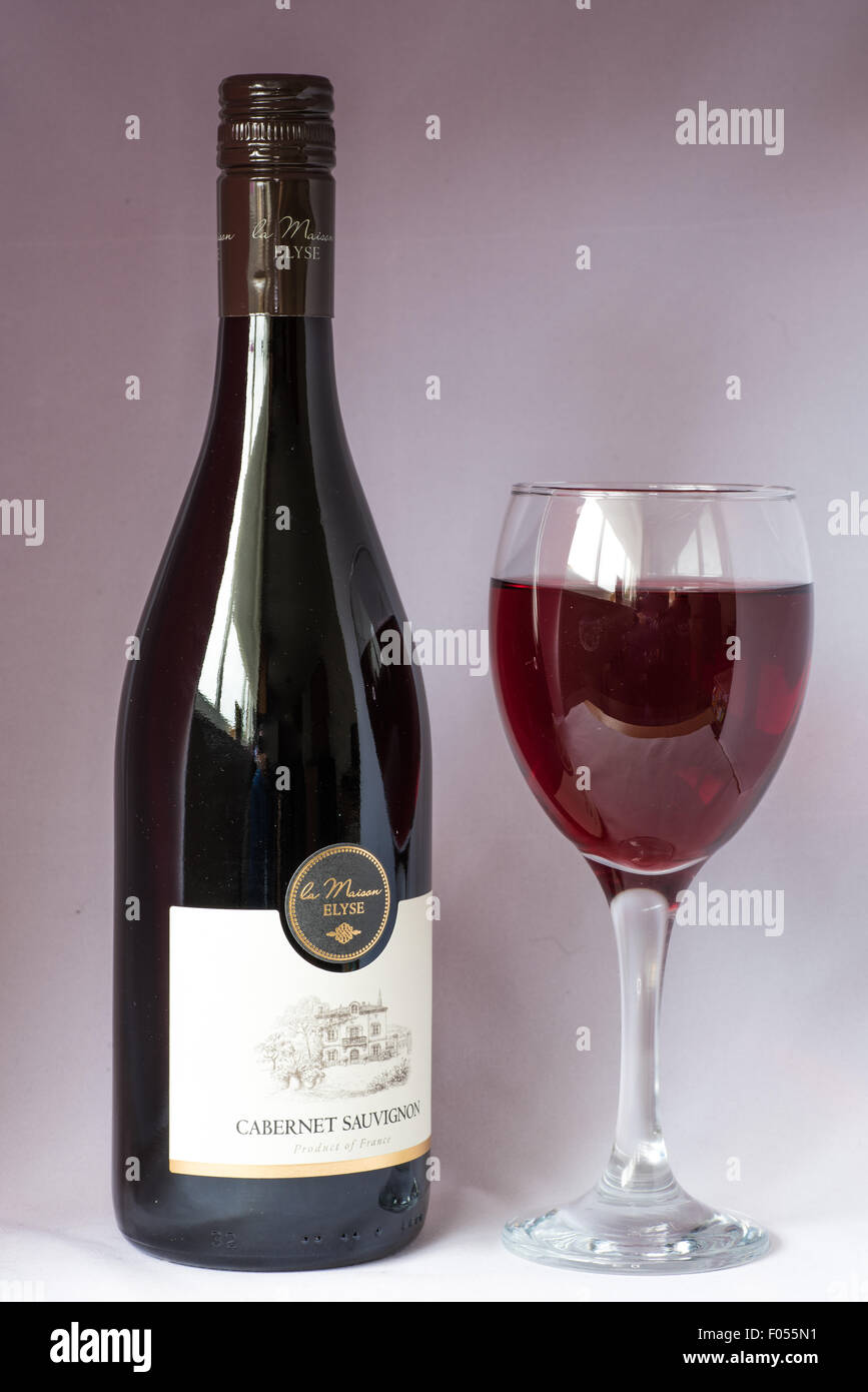 Une bouteille et un verre de vin rouge Cabernet Savignon sur un fond blanc. Banque D'Images