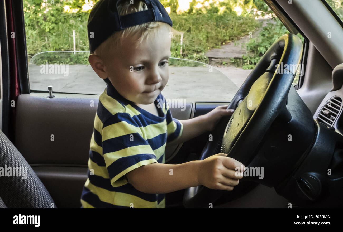 7 août 2015 - Little Boy sitting in car et maintenant le volant © Igor Goloniov/ZUMA/Alamy Fil Live News Banque D'Images