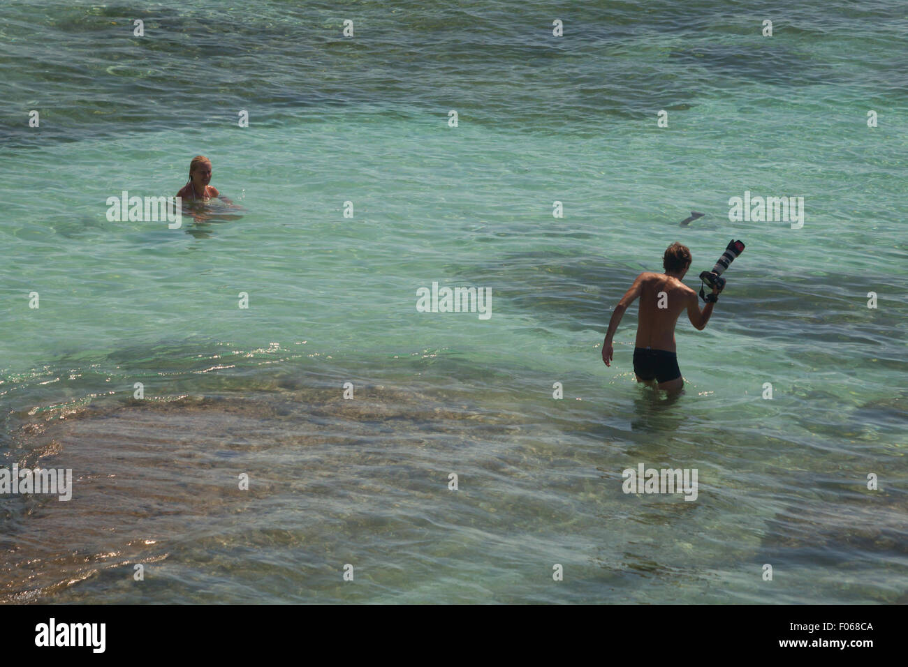 Photographe et femme sur l'eau de mer peu profonde. Plage de Padang-padang, Labuan ait, Kuta Sud, Badung, Bali, Indonésie Banque D'Images