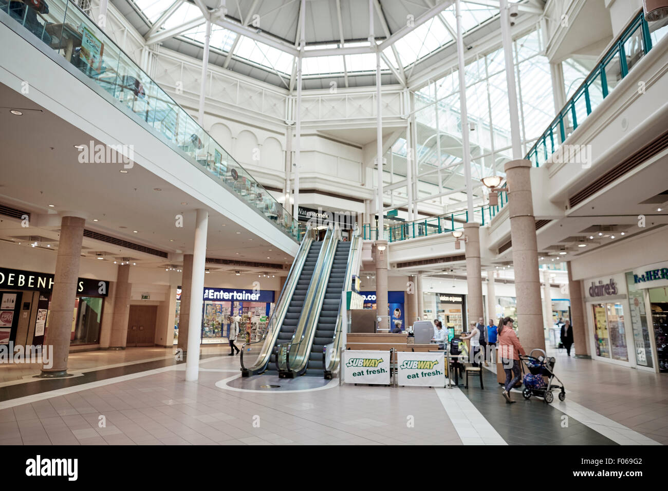 Centre commercial du centre-ville de fusées d'escalators dame maman poussant la pram caractéristiques orné de verre atrium couvert intérieur mall avec Banque D'Images