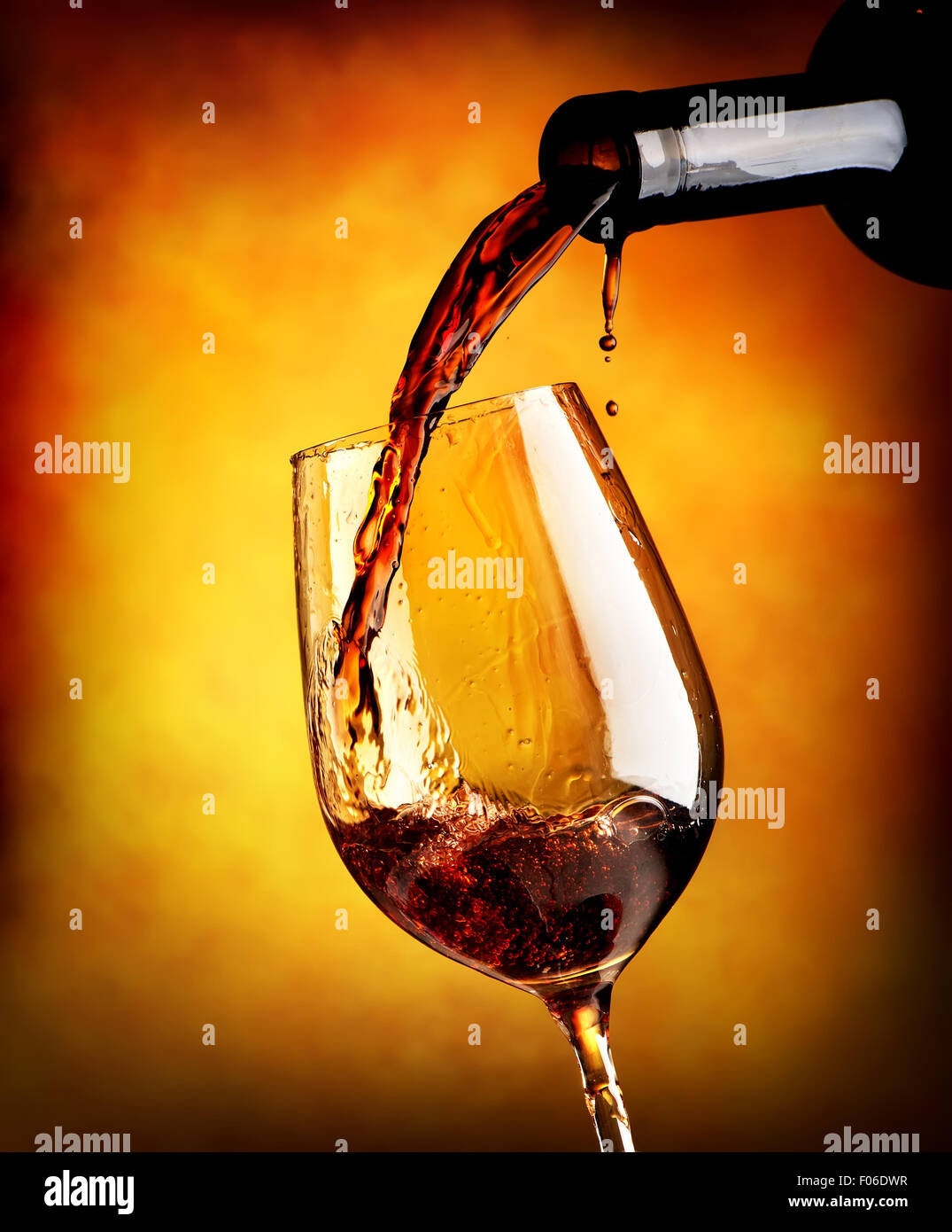 Verser le vin rouge dans un verre sur fond orange Banque D'Images