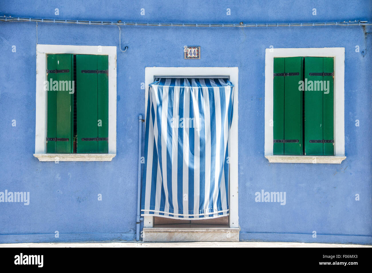 Des volets verts et d'un rideau rayures bleu chambre colorée de l'île de Burano, Venise, Italie Banque D'Images