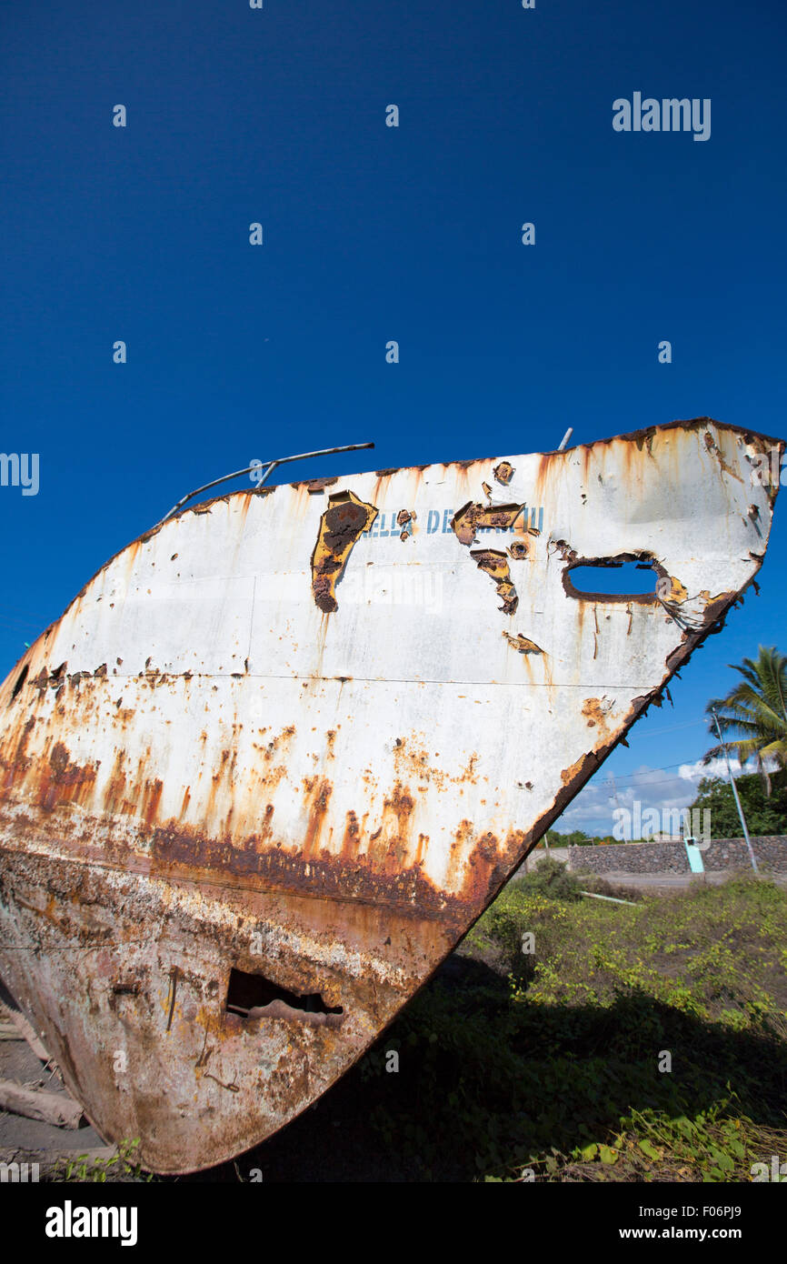 Un vieux bateau contre un ciel bleu clair, surmonté des éléments, est tiré sur la plage dans le port de Puerto Villamil. Banque D'Images