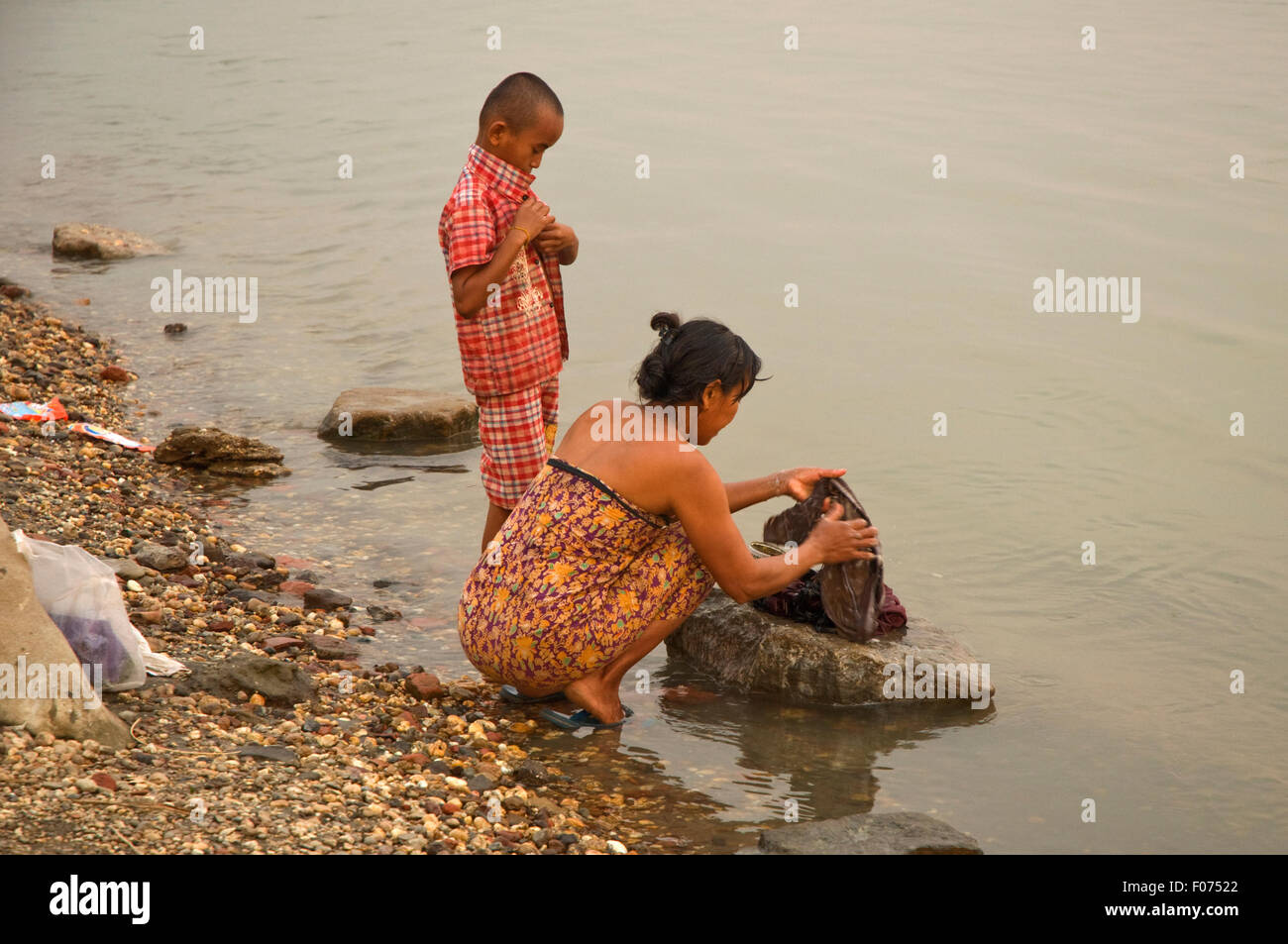 En Asie, LE MYANMAR (BIRMANIE), Bagan, la rivière Irrawaddy, femme (avec jeune garçon) laver les vêtements dans la rivière Banque D'Images