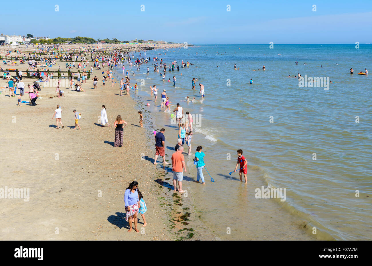 Les gens nager dans la mer sur une plage sur une journée d'été au bord de mer à Littlehampton, West Sussex, Angleterre, Royaume-Uni. Banque D'Images