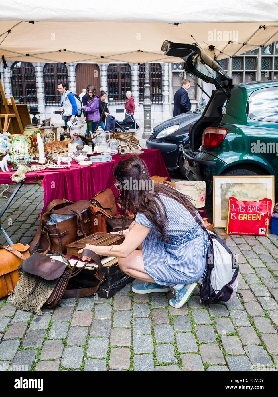 Une jeune femme explore les sacs d'occasion disponible à un décrochage antiques sur la Grand-place dans le centre d'Anvers, Belgique. Banque D'Images