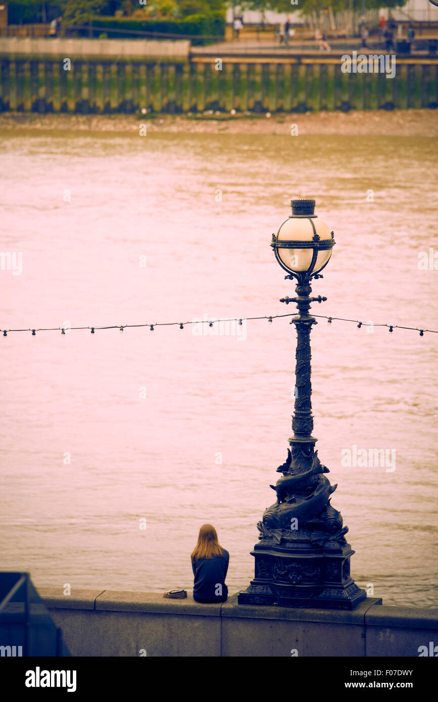 Jeune femme assise à la rivière Thames, London, Royaume-Uni, Europe Banque D'Images