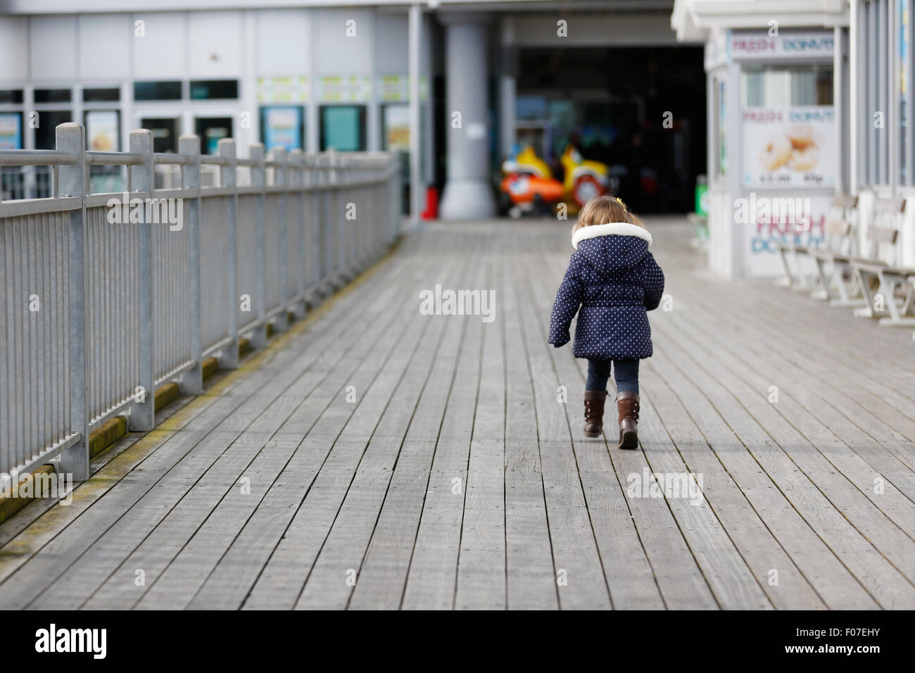 Un enfant court le long d'un quai en bord de mer Banque D'Images