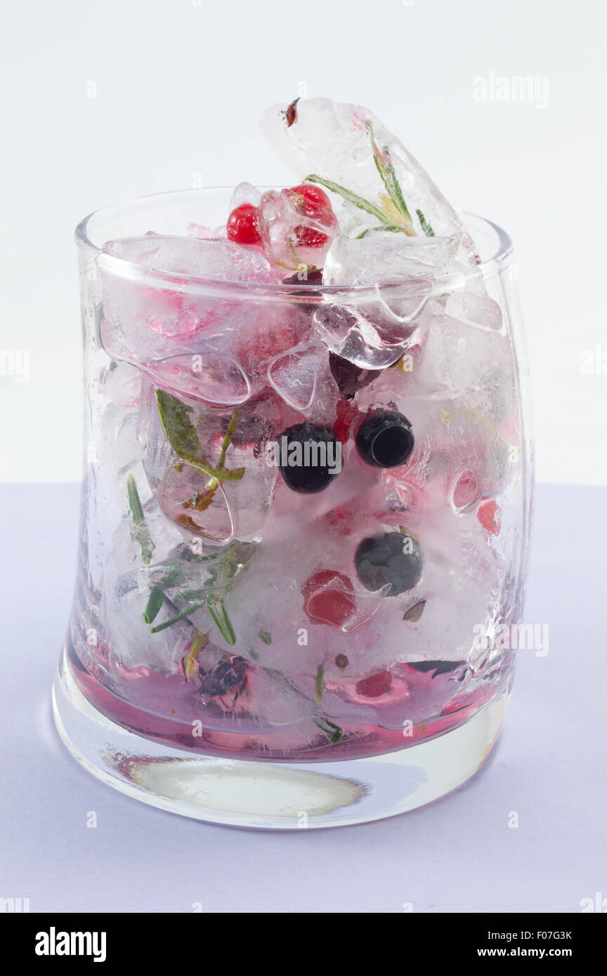 Forêt rouge cocktail de fruits avec de la glace, du citron et des tranches de fruits dans un verre de travers sur fond violet Banque D'Images
