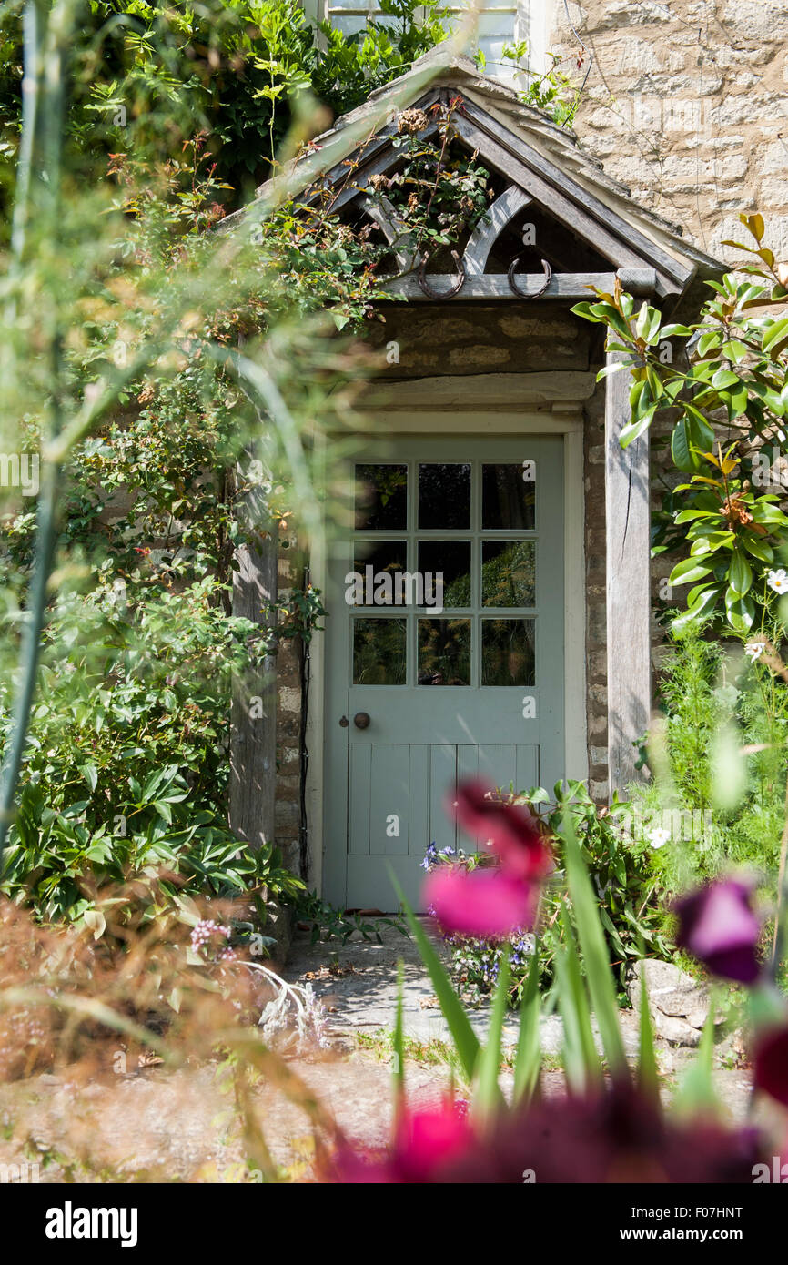 La porte d'un chalet anglais par excellence de fleurs sauvages et d'un porche sous un toit de chaume dans la campagne Banque D'Images