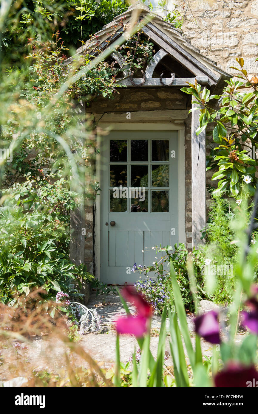 La porte d'un chalet anglais par excellence de fleurs sauvages et d'un porche sous un toit de chaume dans la campagne Banque D'Images