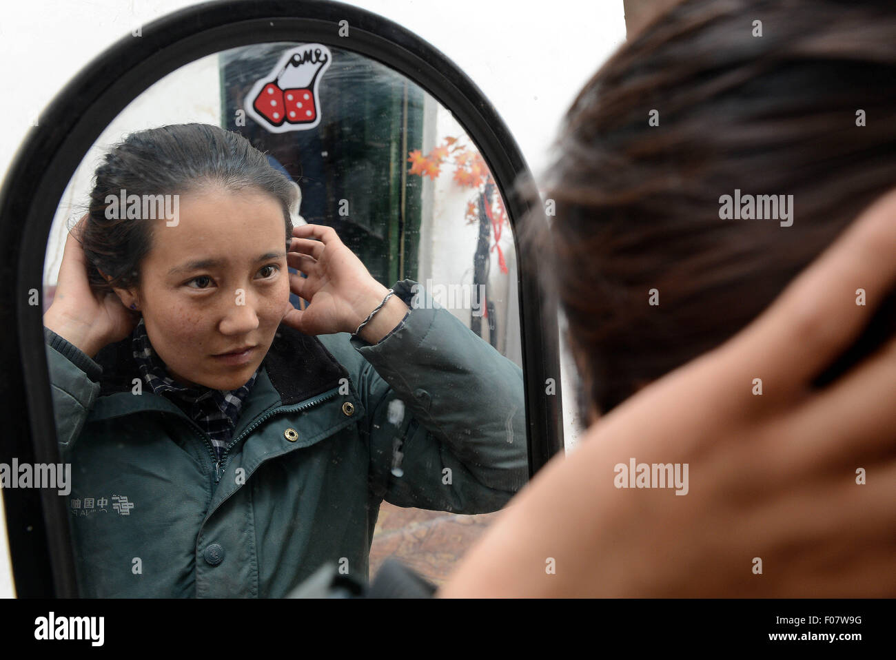 (150810) -- Lhassa, 10 août 2015 (Xinhua) -- Mailwoman Bamu organise ses cheveux avant de partir à Nyima Comté de Naqu Préfecture, sud-ouest de la Chine, région autonome du Tibet, le 11 juin 2015. Bamu, une femme de 26 ans d'ethnie tibétaine, est un mailwoman depuis 2006 pour sept villages éloignés dans Nyima County, qui se situe en moyenne à 4 500 mètres au-dessus du niveau de la mer et couvre plus de 150 000 kilomètres carrés, mais a une population de moins de 30 mille. Le village le plus éloigné est de plus de 100 kilomètres de la ville du comté, et même de certains porte-à-porte, dist Banque D'Images