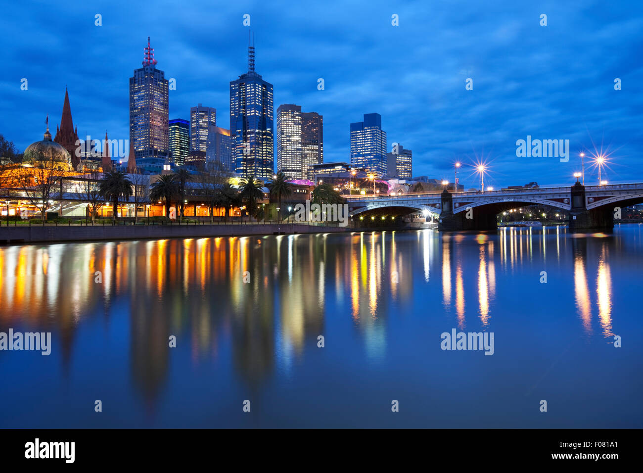 Les toits de Melbourne, en Australie avec la gare de Flinders Street et les Princes Bridge de l'autre côté de la rivière Yarra, dans la nuit. Banque D'Images