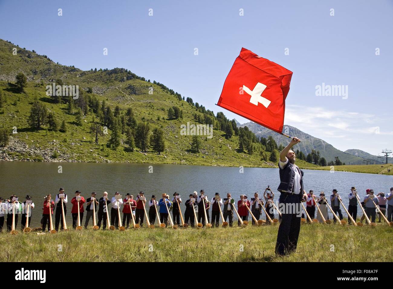 Les personnes à la réunion de cor des Alpes et l'homme en face en agitant drapeau suisse en Valais, Suisse Banque D'Images