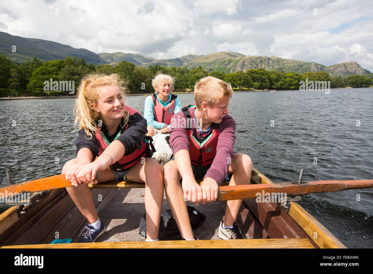 Une femme et deux adolescents dans une barque sur l'eau de Coniston dans le Lake District, Cumbria, Royaume-Uni. Banque D'Images