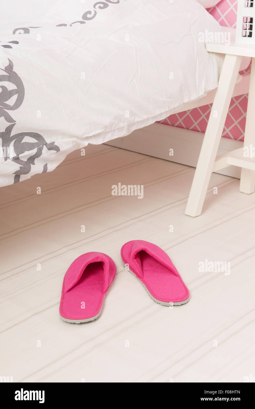 Chaussons rose sous le lit dans la chambre Banque D'Images