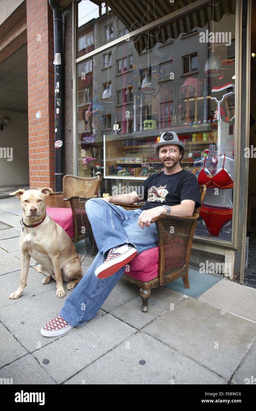 Commerçant assis sur une chaise avec chien contre shop à Stuttgart, Allemagne Banque D'Images