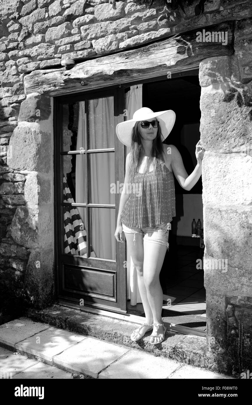 Belle jeune femme dans la vingtaine, portant un chapeau à grand soleil à l'extérieur de sa maison de vacances gite de France Lot Région Banque D'Images
