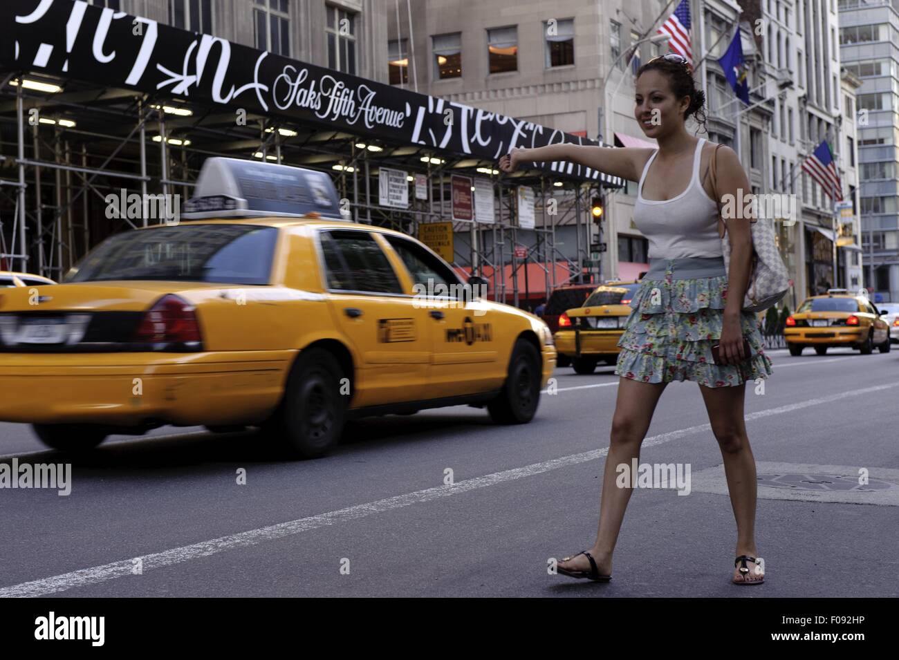 Woman waving dehors pour un taxi sur la route, New York Banque D'Images