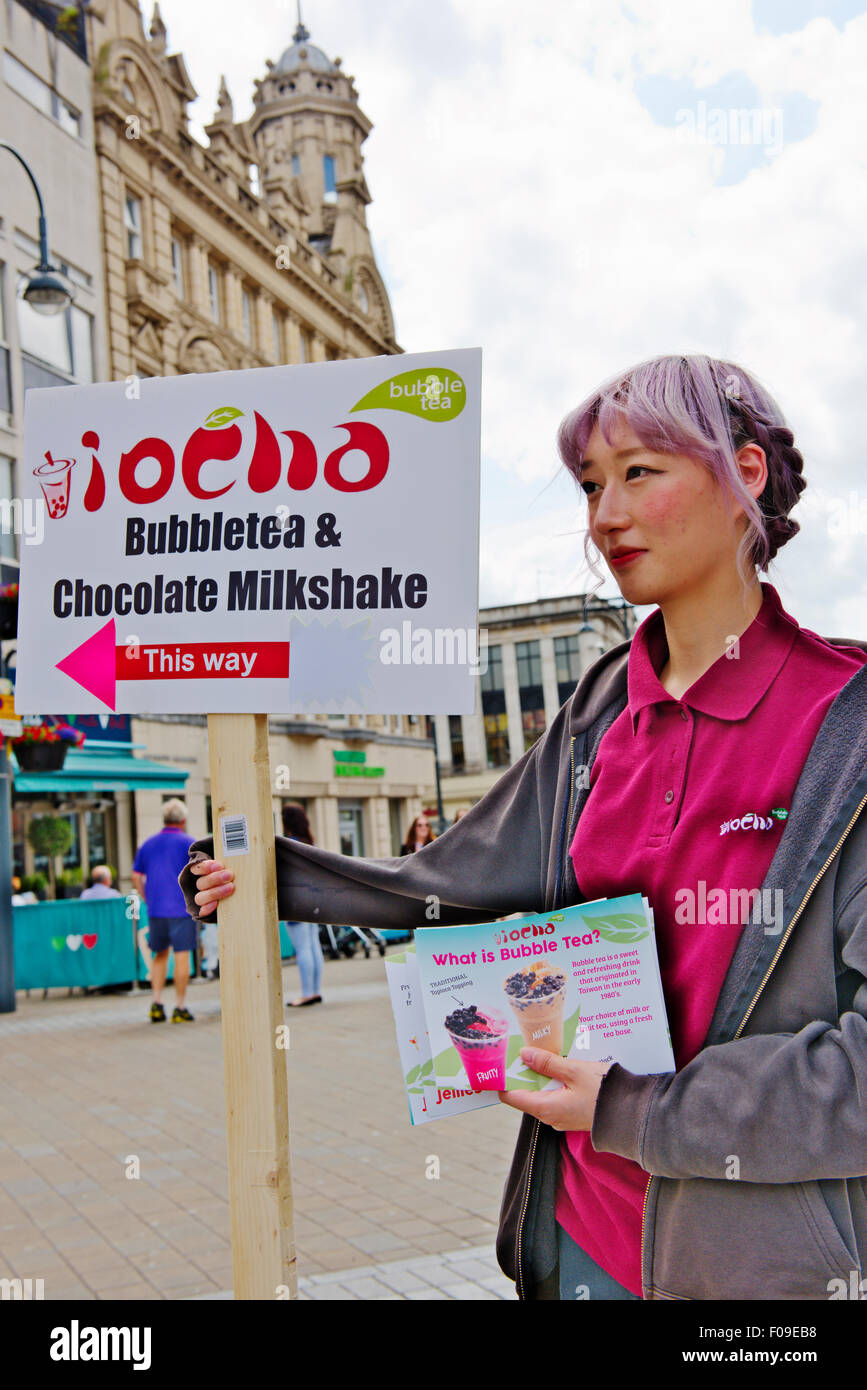 Jolie femme tenant une pancarte publicitaire pour snack shop local, Leeds, Royaume-Uni Banque D'Images