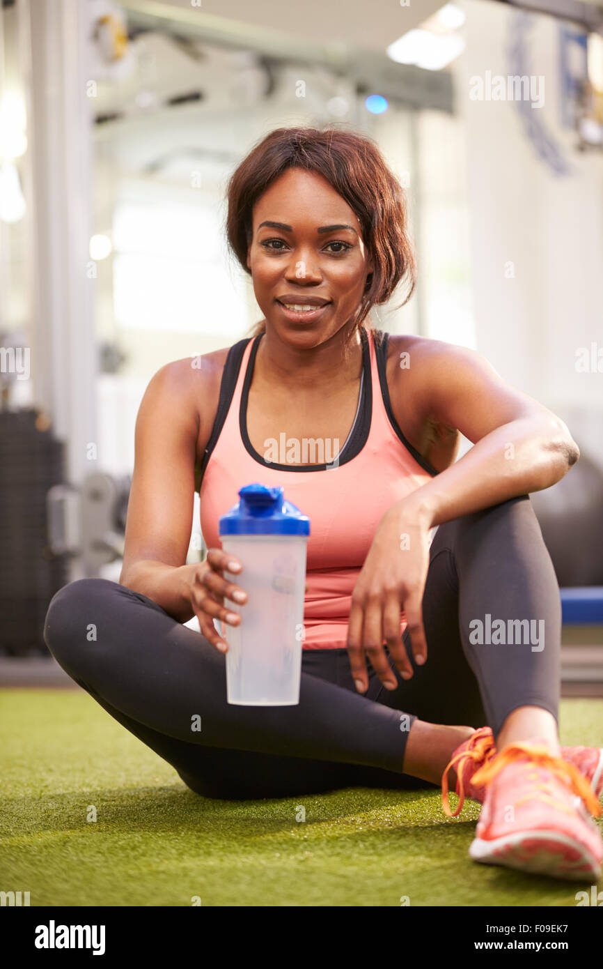Jeune femme à boire de l'eau dans une salle de sport, vertical shot Banque D'Images