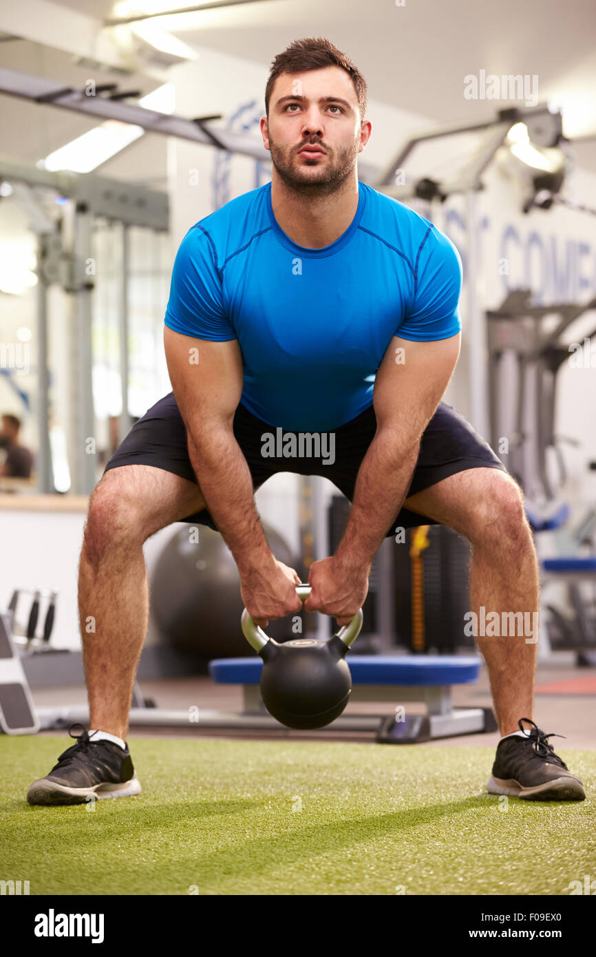 Man exercising in a gym avec un poids kettlebell, vertical shot Banque D'Images