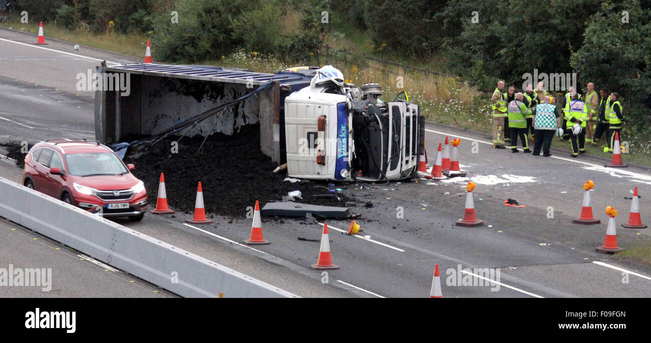 M3, Farnborough, Hampshire, Royaume-Uni. 10 août, 2015. M3 près de Farnborough montre GV de la scène après une collision avec un poids lourds d'entretien des routes véhicule stationné sur la bande d'arrêt d'urgence. Le camion était une protection aux camions de récupération qui se remet d'un automobiliste en panne. Le VHG après la collision à grande vitesse que s'est immobilisée sur le côté après le licenciement de son chargement sur voies 1 et 2 du transport principal. Deux personnes ont été transportées à l'hôpital, l'une par Air Ambulance la deuxième par la route. Crédit : Jason Kay/Alamy Live News Banque D'Images