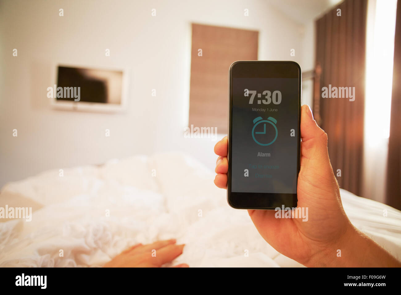 Point de vue de Droit de la personne dans le lit de désactiver l'alarme de téléphone Banque D'Images