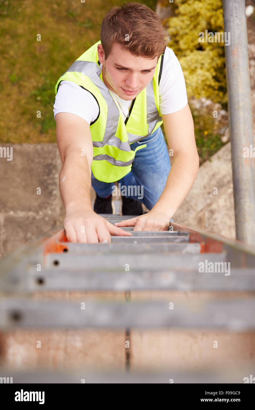 Construction Worker Climbing Ladder sur chantier Banque D'Images