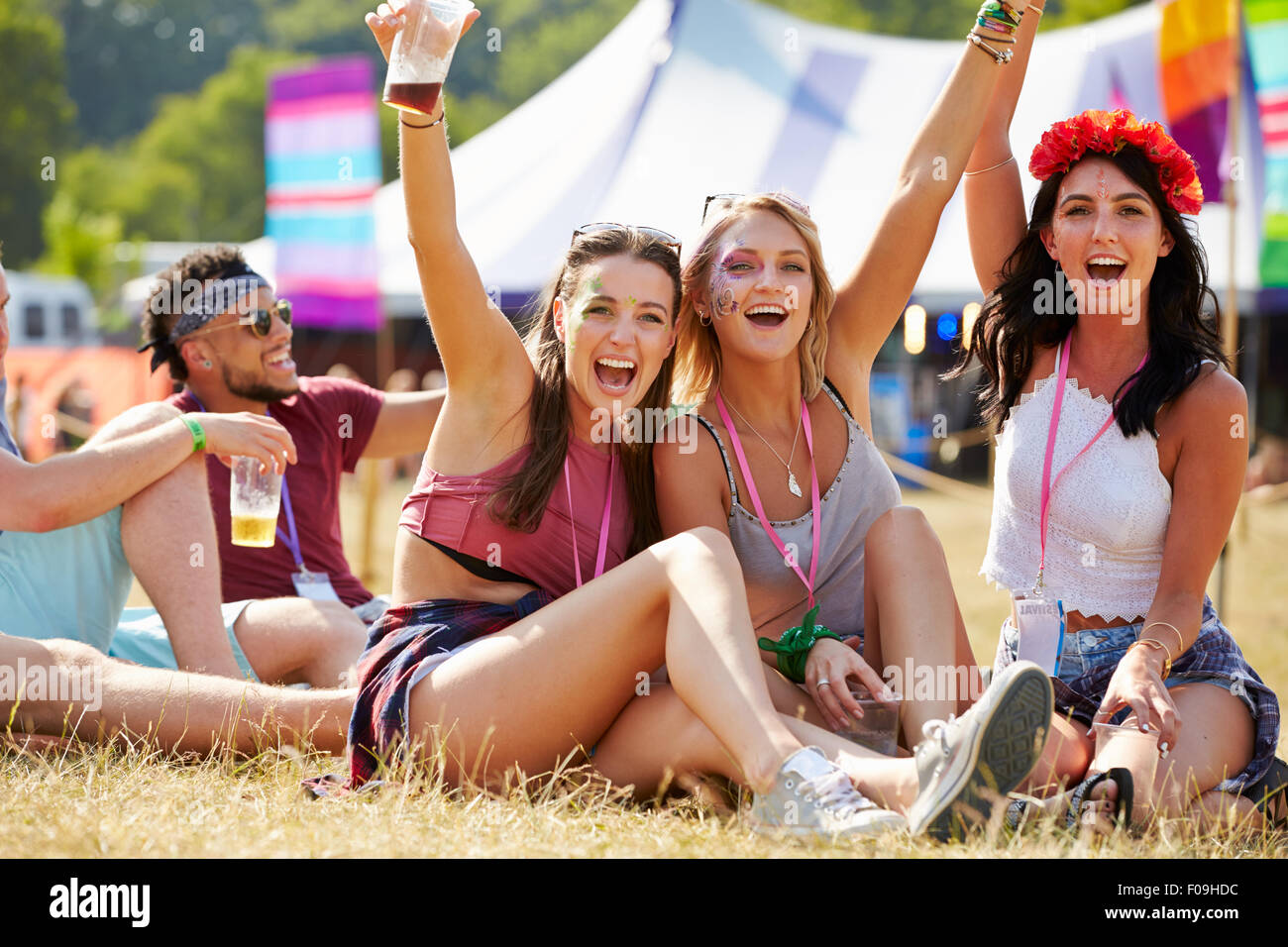 Amis assis sur l'herbe cheering at un festival de musique Banque D'Images