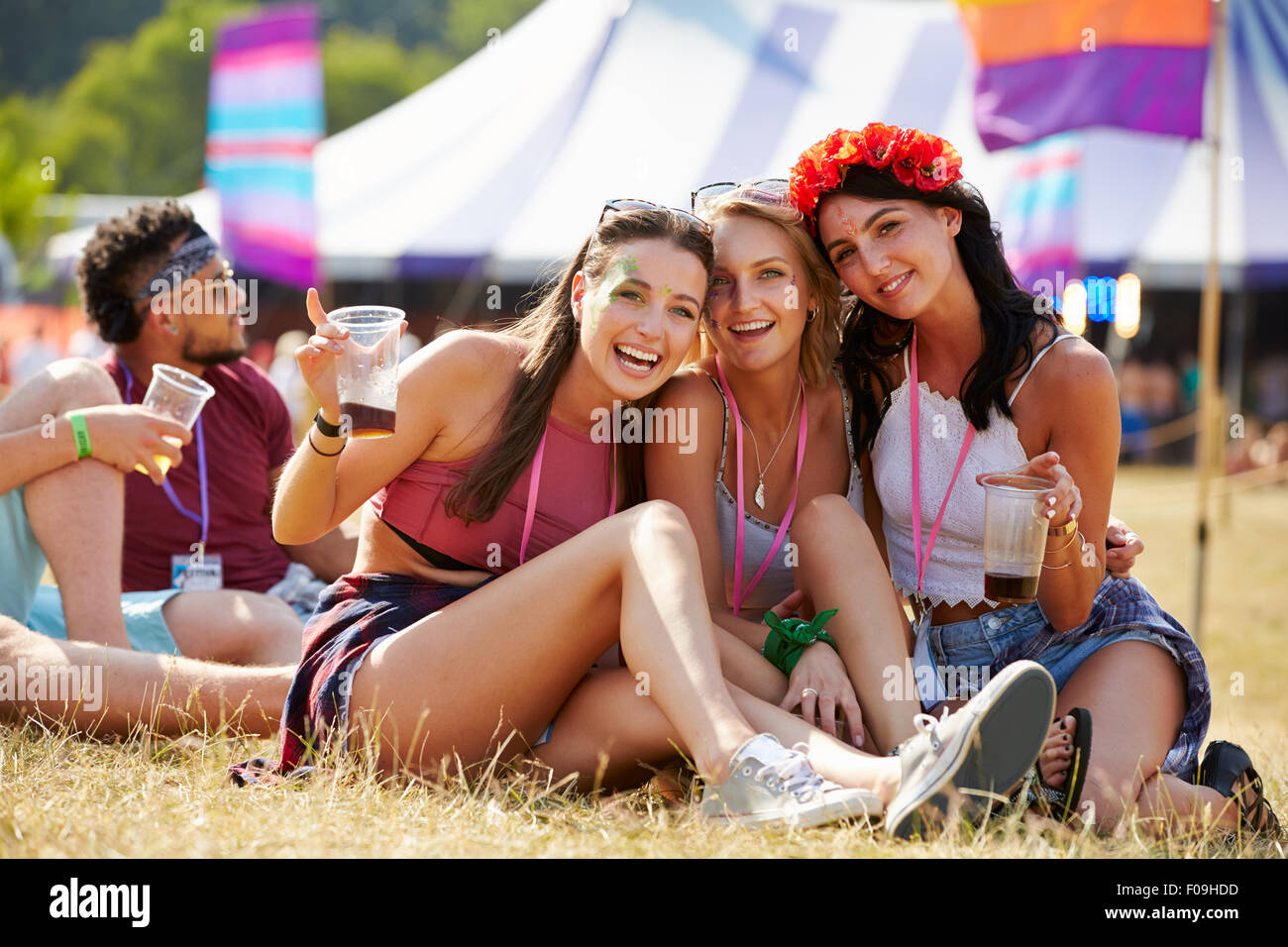Amis assis sur l'herbe s'amusant à un festival de musique Banque D'Images