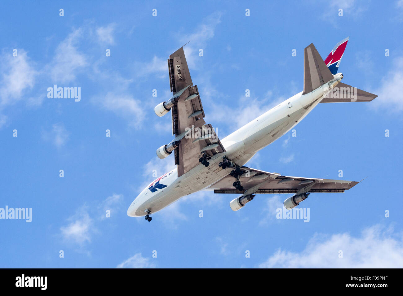 Boeing 747 MK transports l'écorchage passage avec ses roues vers le bas tout en s'approche de l'aéroport local. Ciel bleu et blanc, quelques nuages vaporeux. Banque D'Images