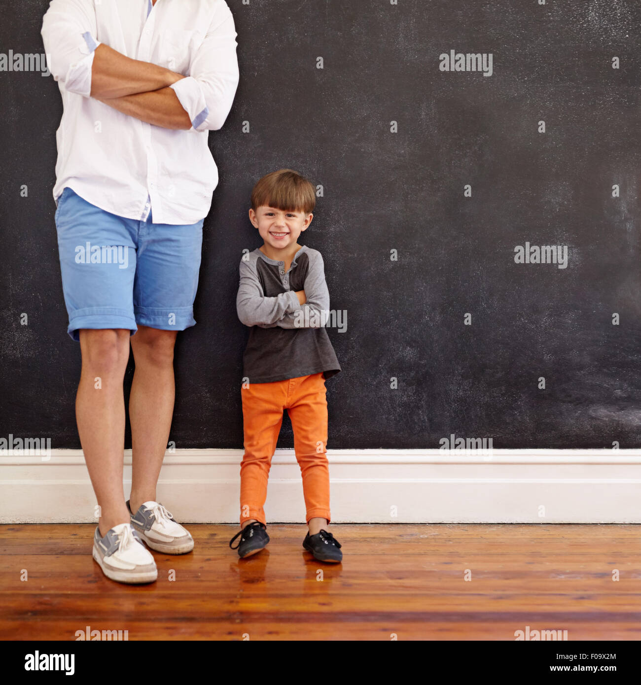 Tourné à l'intérieur du petit garçon debout à côté de son père, avec les mains pliées et souriant. Cropped shot of young man en été porter w Banque D'Images