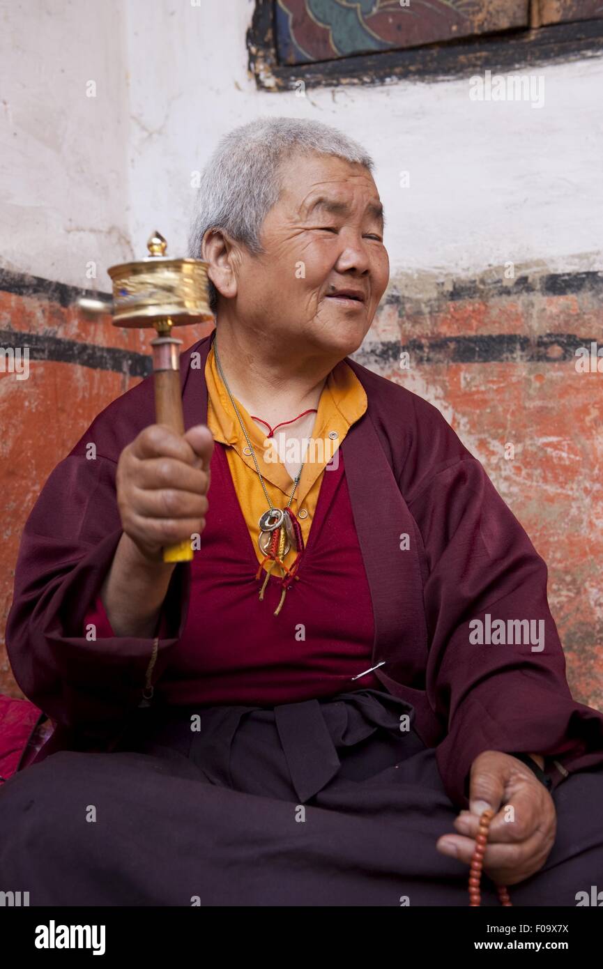 Senior woman spinning à prières en priant dans Jampey Lhakhang temple, Bhoutan Banque D'Images