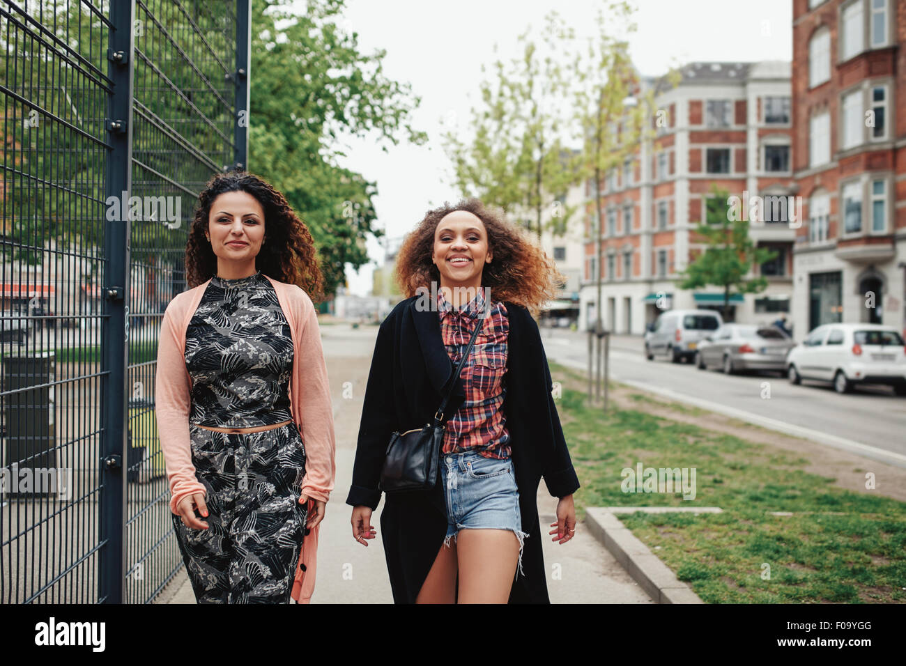 Tourné en plein air de deux copines marcher à travers la ville. Heureux les jeunes femmes à marcher ensemble le long d'une rue de la ville. Banque D'Images