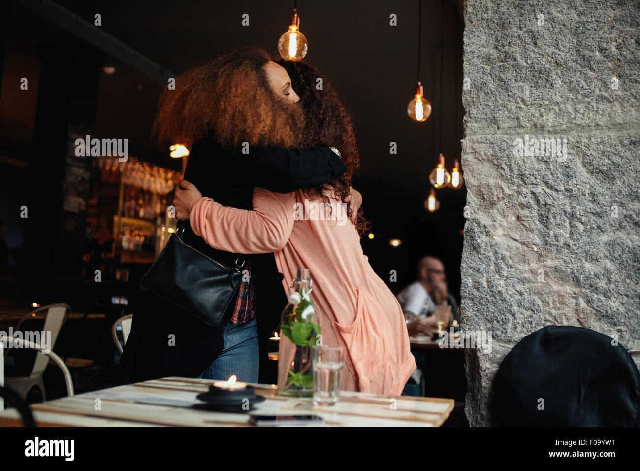 Deux jeunes femmes réunis dans un restaurant. Friends hugging mutuellement dans un café. Banque D'Images