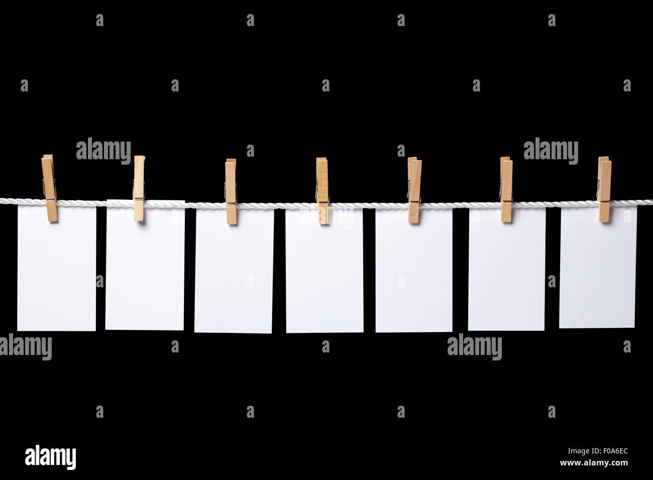 Image de sept petites feuilles de papier blanc accroché avec corde linge sur. La composition est isolé sur fond noir. Le rela Banque D'Images
