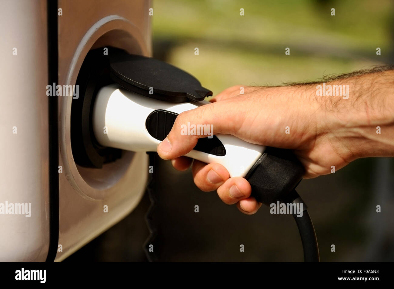 Main tenant une prise électrique pour recharger en voiture électrique Banque D'Images