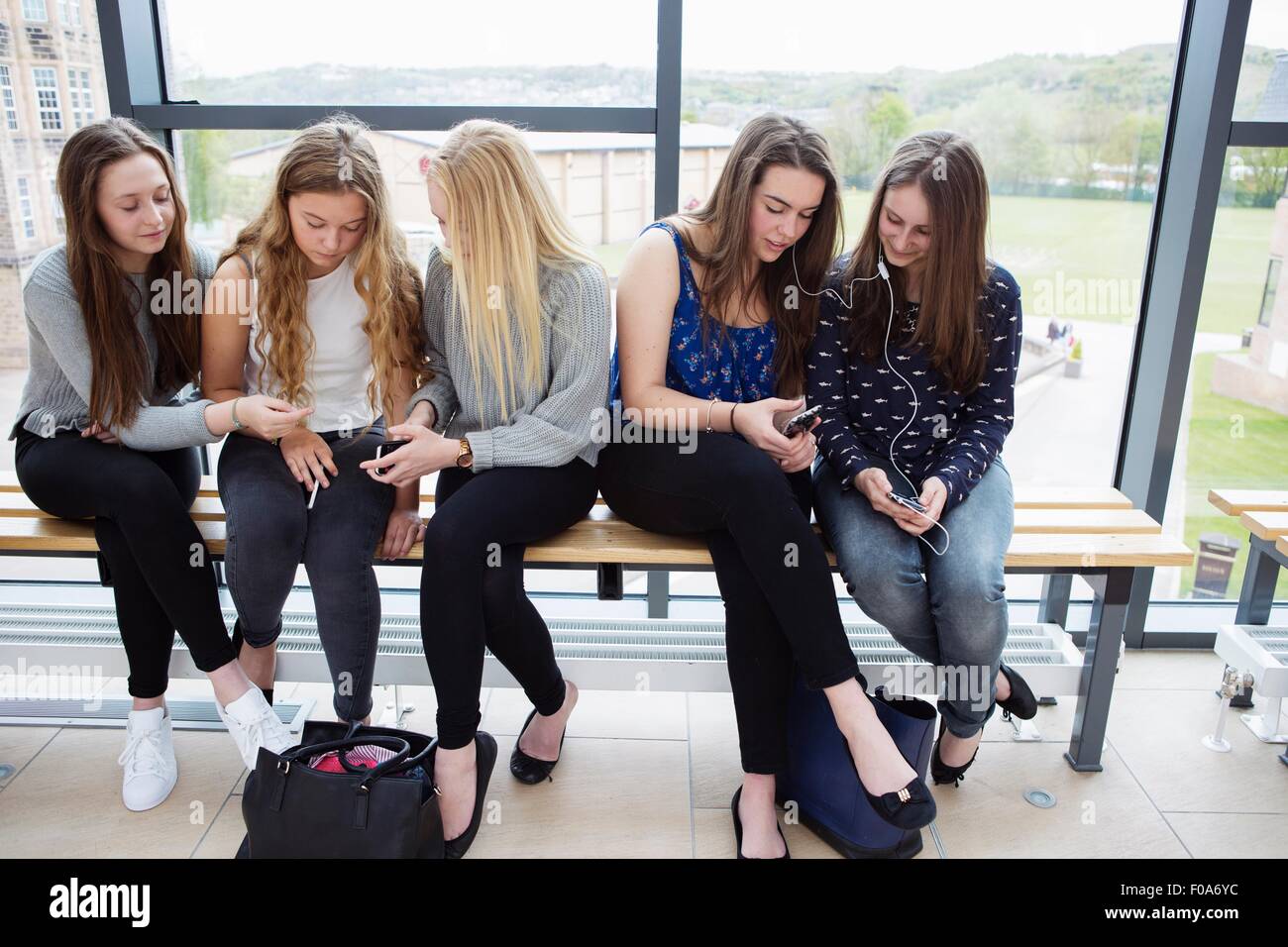 Les jeunes filles à l'aide du smartphone sur le banc Banque D'Images