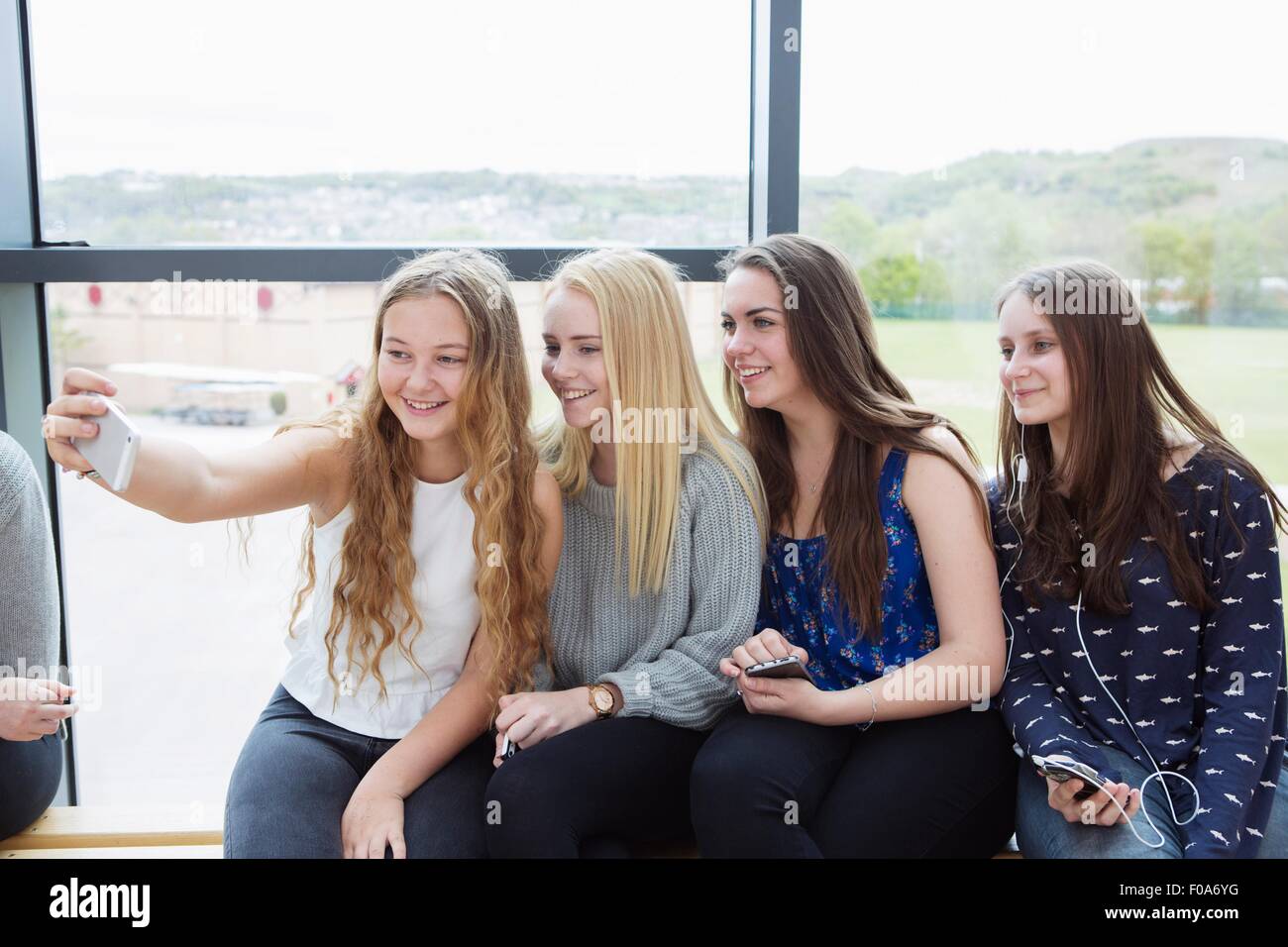 Les adolescentes en tenant avec banc sur smartphone selfies Banque D'Images