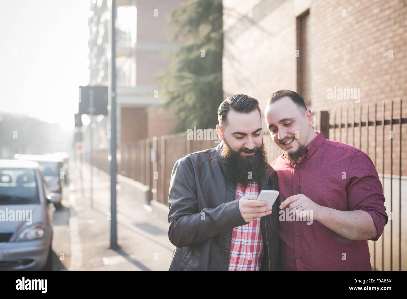 Couple Gay à l'aide du smartphone sur le trottoir Banque D'Images